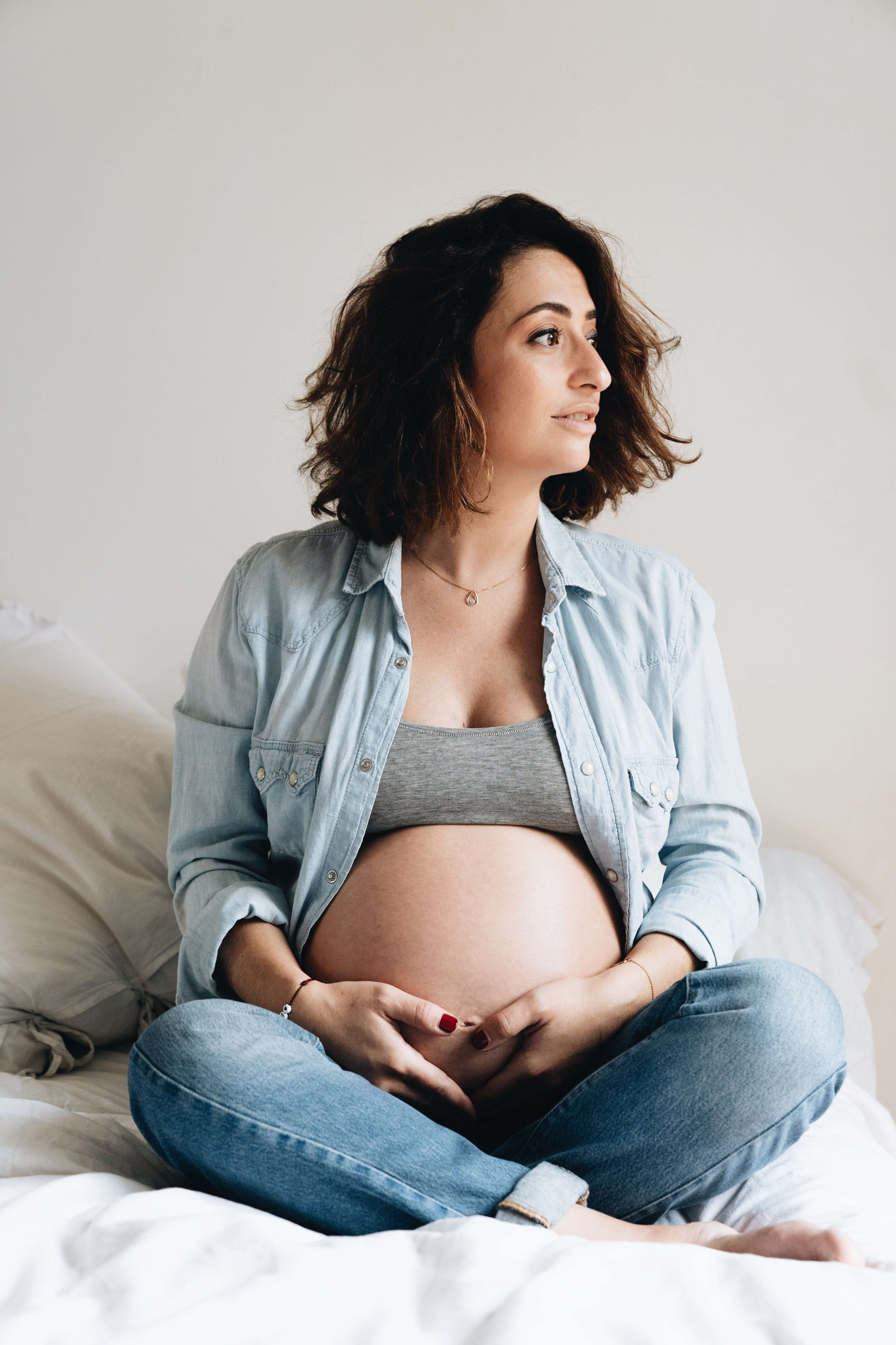 femme enceinte assise en jeans ventre nu